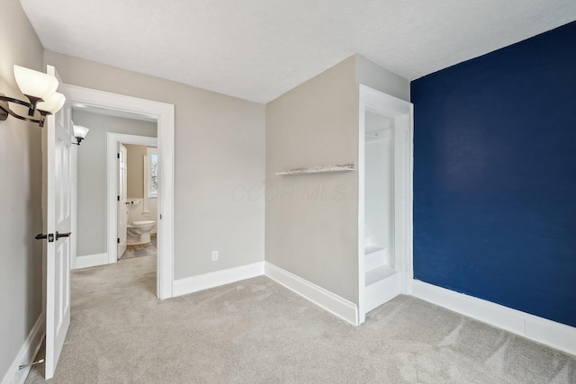 unfurnished bedroom with baseboards, a textured ceiling, and light colored carpet