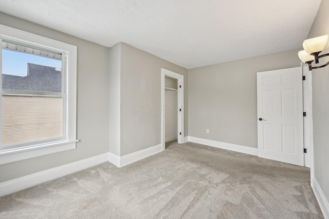 unfurnished bedroom featuring light carpet and baseboards