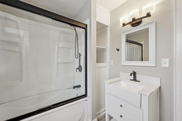 bathroom with enclosed tub / shower combo, a textured ceiling, and vanity