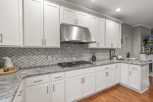 kitchen featuring a peninsula, light wood-type flooring, under cabinet range hood, stainless steel gas stovetop, and white cabinetry