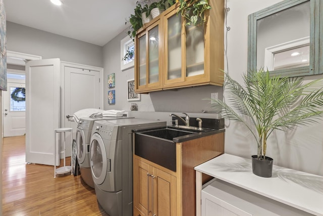 laundry room featuring cabinet space, light wood-style flooring, separate washer and dryer, and a wealth of natural light