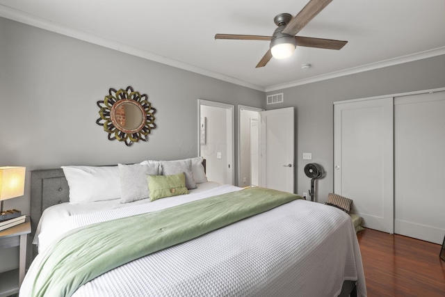 bedroom featuring wood finished floors, a ceiling fan, visible vents, a closet, and crown molding