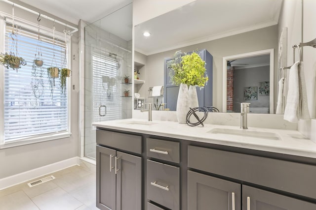 bathroom with a stall shower, crown molding, visible vents, and a sink