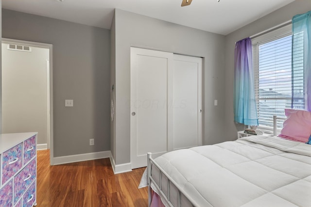 bedroom featuring a closet, visible vents, ceiling fan, wood finished floors, and baseboards