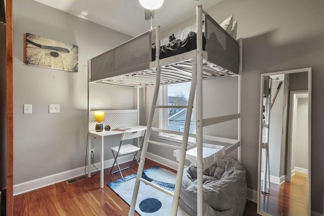 bedroom featuring visible vents, baseboards, and wood finished floors