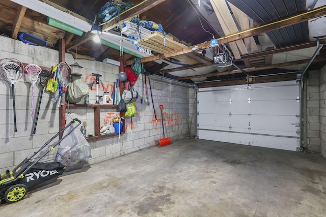 garage featuring concrete block wall and a garage door opener