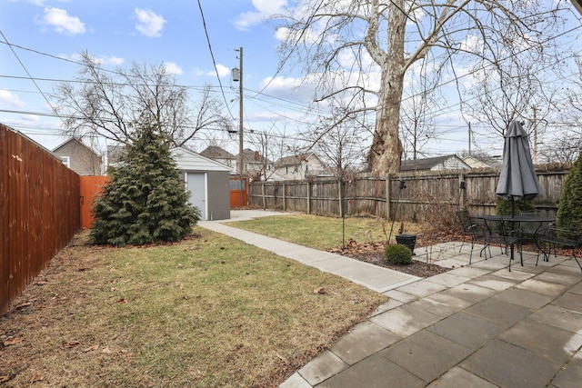 view of yard featuring a storage shed, a fenced backyard, a patio, and an outbuilding