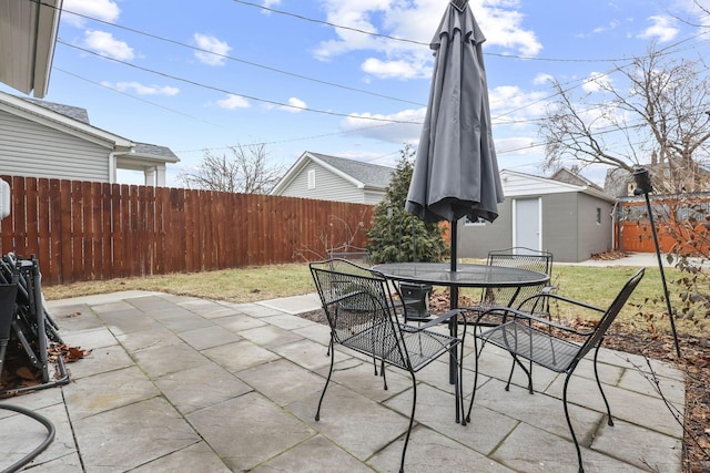 view of patio with outdoor dining space, a fenced backyard, and an outdoor structure