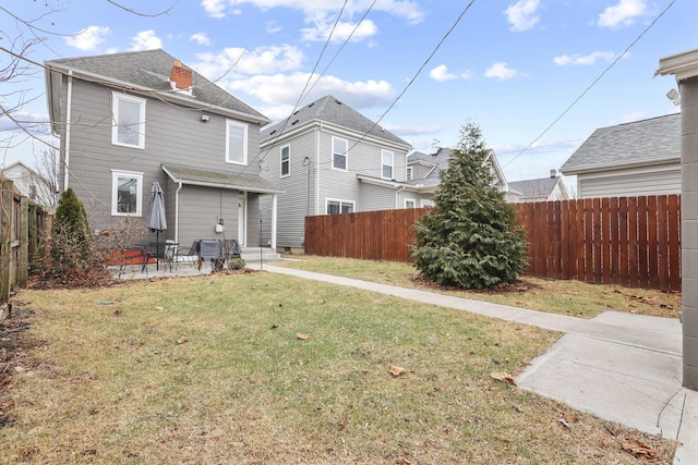 rear view of house with a yard, a patio, a shingled roof, entry steps, and a fenced backyard