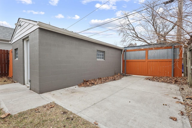 view of home's exterior with concrete block siding and fence