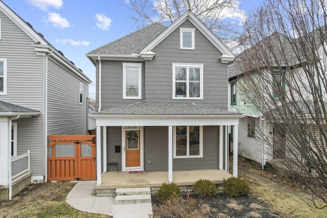 traditional home with a porch and roof with shingles