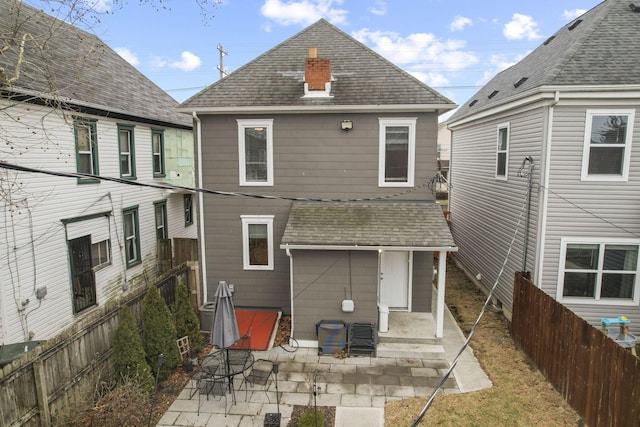 back of property featuring roof with shingles, a patio, and fence