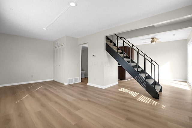 unfurnished living room featuring visible vents, baseboards, wood finished floors, and stairs