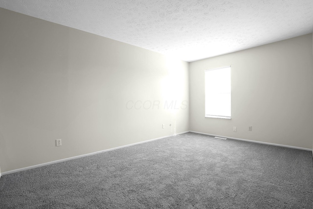 carpeted spare room featuring baseboards and a textured ceiling