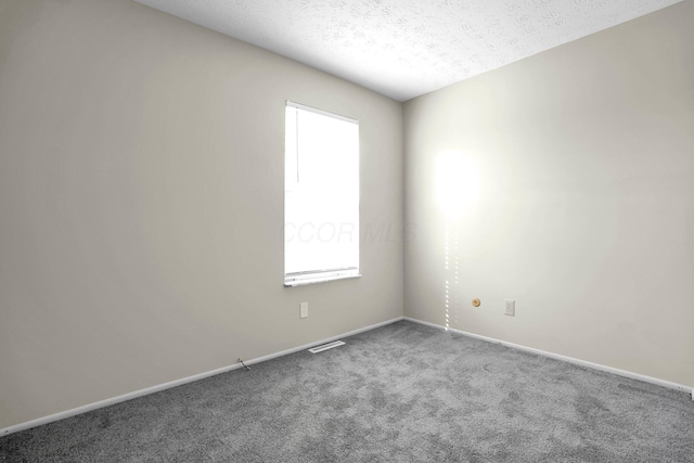 carpeted empty room with visible vents, a textured ceiling, and baseboards