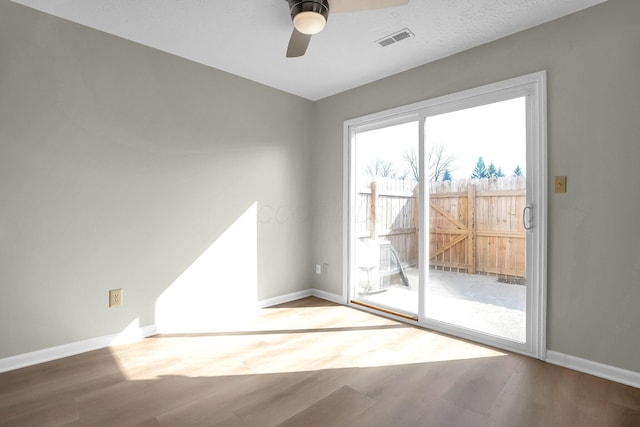 unfurnished room with visible vents, baseboards, ceiling fan, and wood finished floors