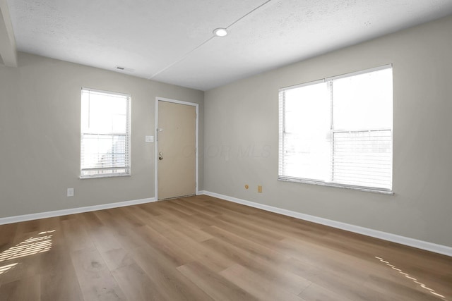 unfurnished room featuring wood finished floors, baseboards, visible vents, and a textured ceiling