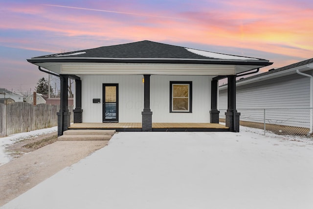 view of front of house with a shingled roof, fence, and a porch