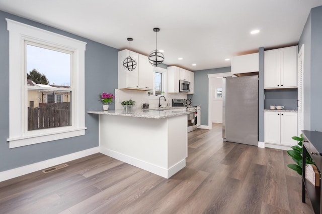 kitchen featuring stainless steel appliances, white cabinetry, and hanging light fixtures