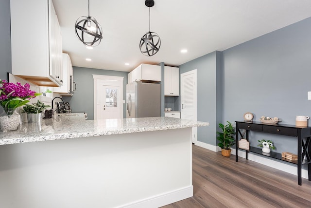 kitchen featuring a peninsula, decorative light fixtures, white cabinets, and stainless steel fridge with ice dispenser