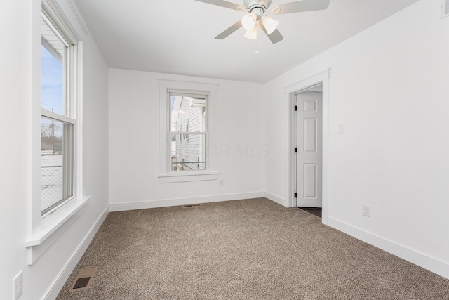 carpeted empty room featuring a ceiling fan, visible vents, and baseboards