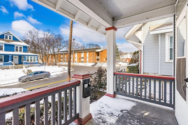 snow covered back of property featuring a residential view and a porch