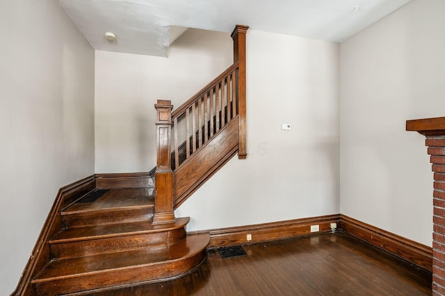 stairs with baseboards, visible vents, and wood finished floors