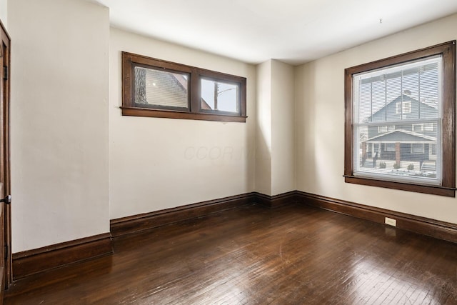 spare room with dark wood-style flooring and baseboards