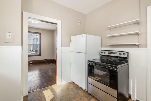 kitchen with a wainscoted wall, stainless steel electric range oven, dark wood-type flooring, freestanding refrigerator, and open shelves