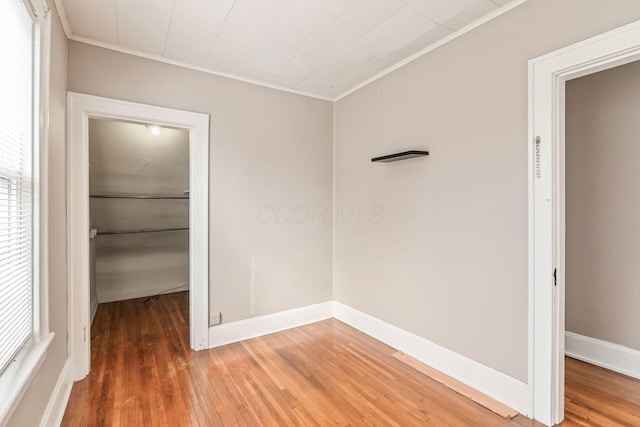 empty room with crown molding, baseboards, and wood finished floors