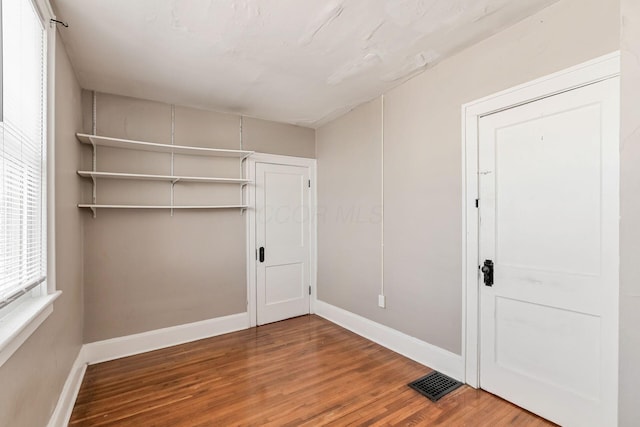 unfurnished bedroom with visible vents, a closet, baseboards, and wood finished floors