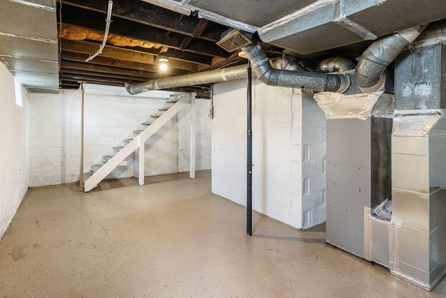 unfinished basement featuring stairway and heating unit