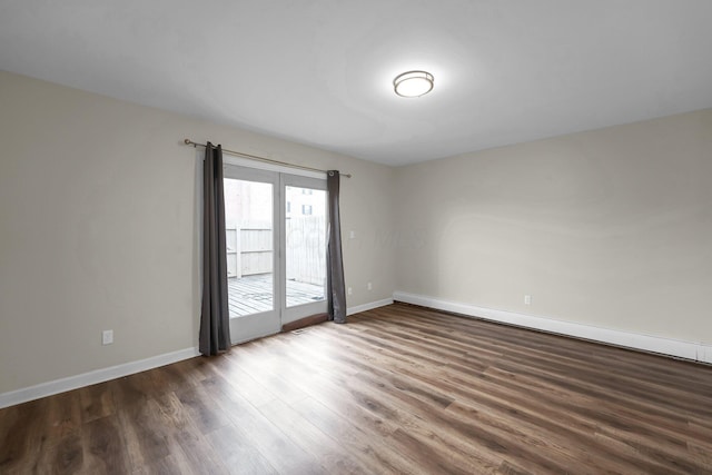 spare room with baseboards and wood finished floors