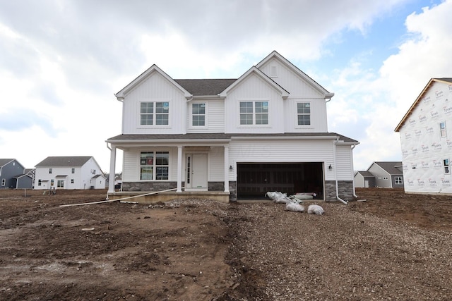 view of front of house with a garage, stone siding, covered porch, and board and batten siding