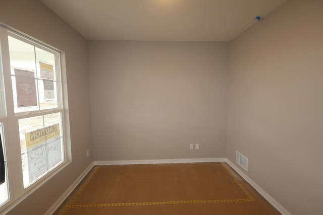 unfurnished room featuring baseboards and visible vents