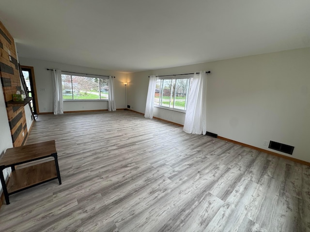 unfurnished living room with wood finished floors, visible vents, and baseboards