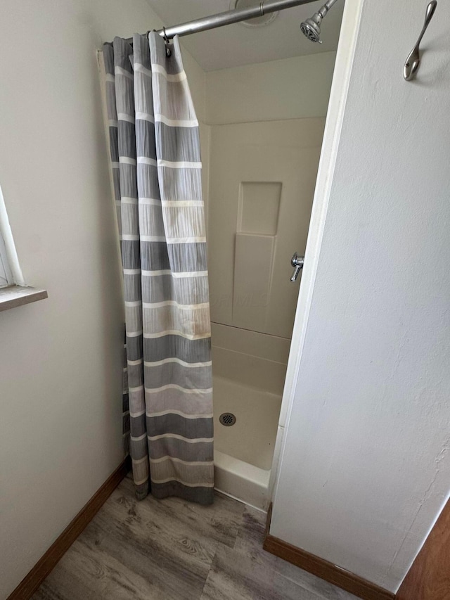 bathroom with a shower stall, baseboards, and wood finished floors