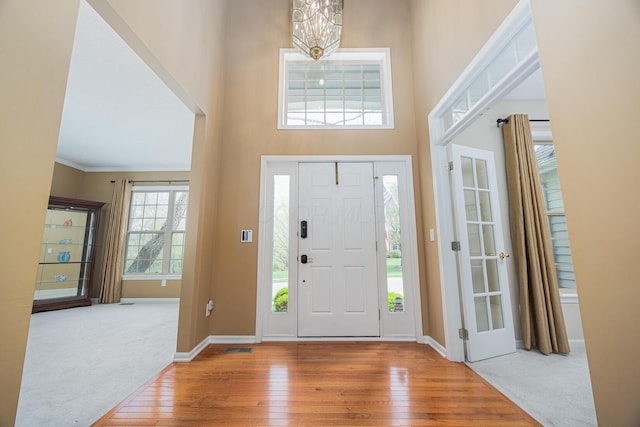 413 Ashmoore Cir E, Powell, OH 43065 - foyer entrance with carpet, baseboards, ornamental molding, a towering ceiling, and wood finished floors