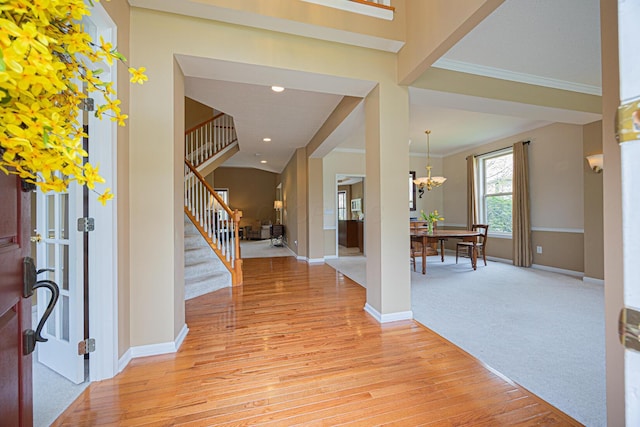 413 Ashmoore Cir E, Powell, OH 43065 - entryway with crown molding, stairway, baseboards, an inviting chandelier, and light wood-type flooring