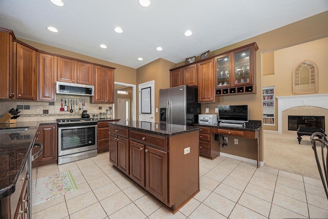 413 Ashmoore Cir E, Powell, OH 43065 - kitchen with light tile patterned flooring, dark stone countertops, a kitchen island, and stainless steel appliances