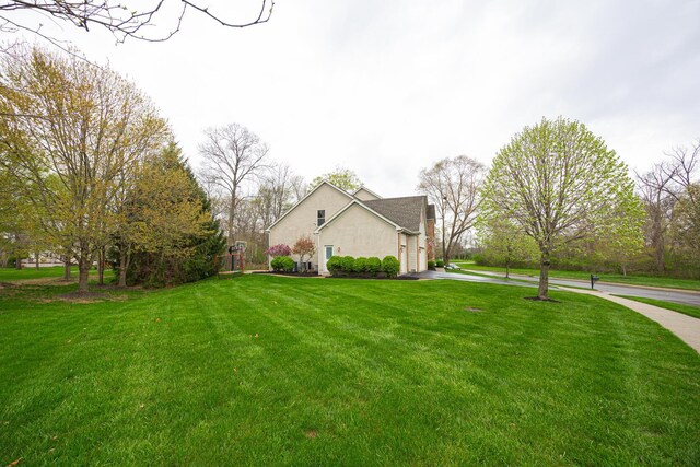 413 Ashmoore Cir E, Powell, OH 43065 - view of property exterior with concrete driveway, a lawn, and stucco siding