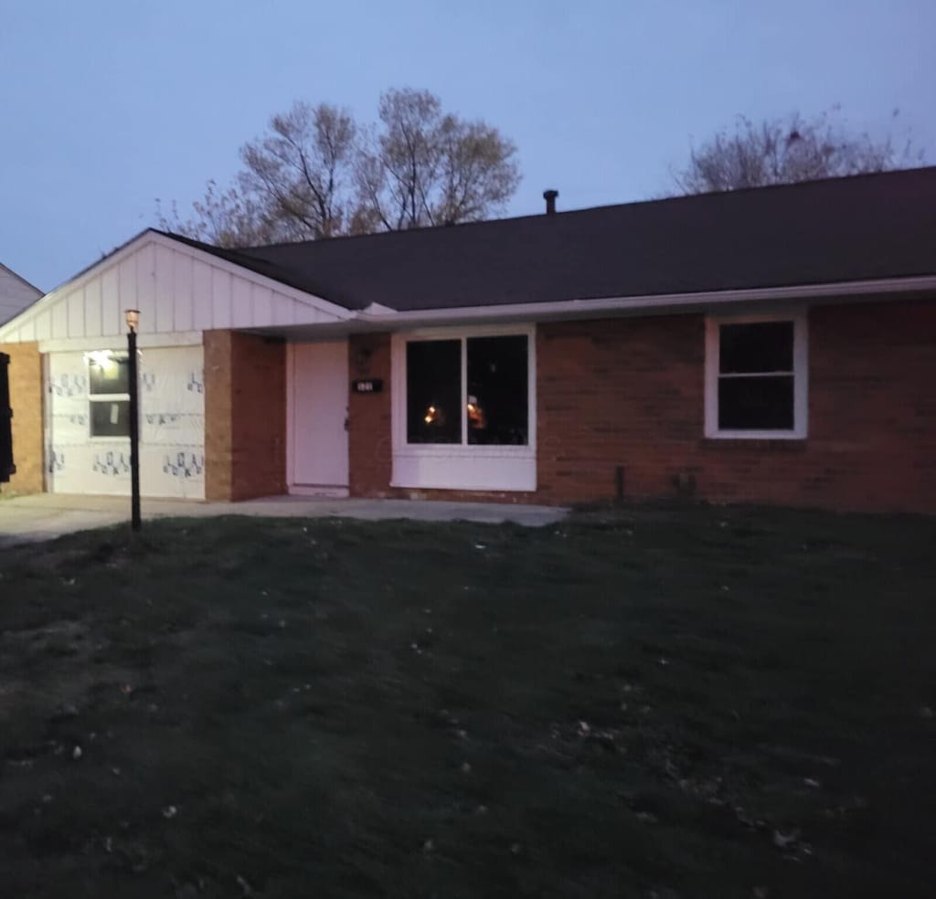 single story home with a garage, board and batten siding, and a front yard