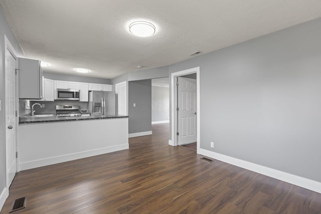 kitchen featuring a sink, visible vents, white cabinetry, appliances with stainless steel finishes, and dark countertops