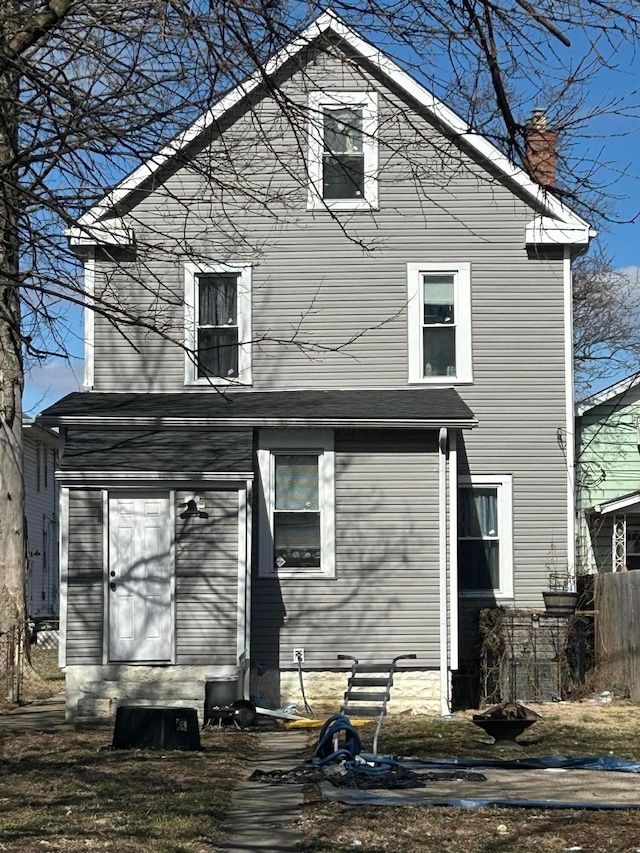 back of property with entry steps, a chimney, and fence