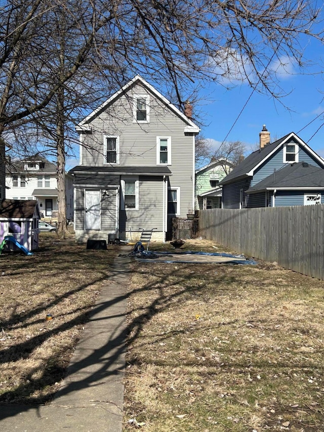 rear view of property featuring entry steps and fence