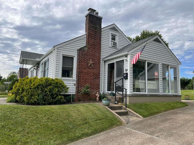 view of front of home featuring a front yard, roof with shingles, and a chimney