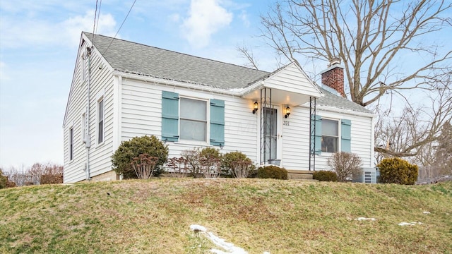 view of front of house featuring a shingled roof, a chimney, and a front lawn