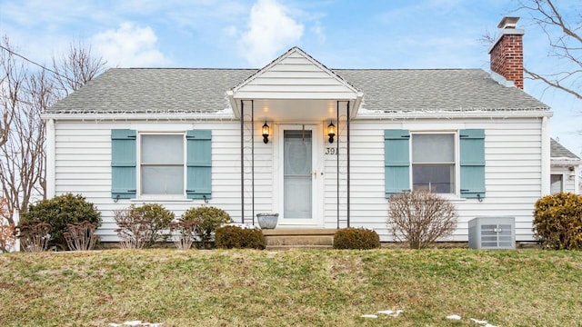 bungalow featuring roof with shingles, a chimney, central AC unit, a front yard, and entry steps