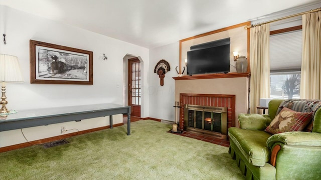 sitting room with baseboards, visible vents, arched walkways, carpet flooring, and a brick fireplace