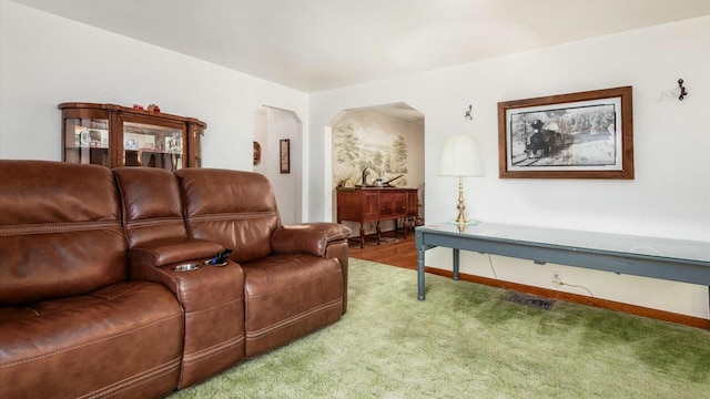 living area featuring carpet floors, visible vents, baseboards, and arched walkways